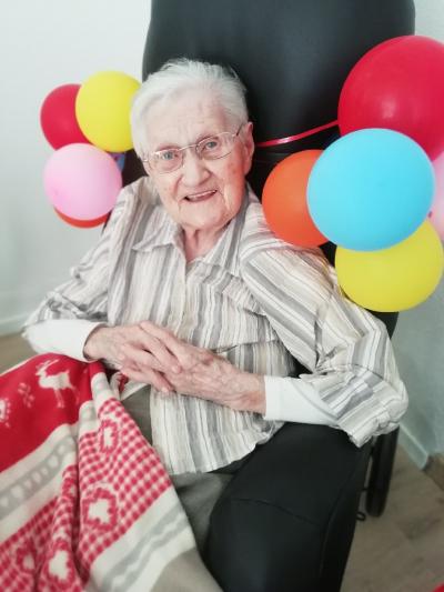 personne âgée dans fauteuil noir avec des ballons multicolores